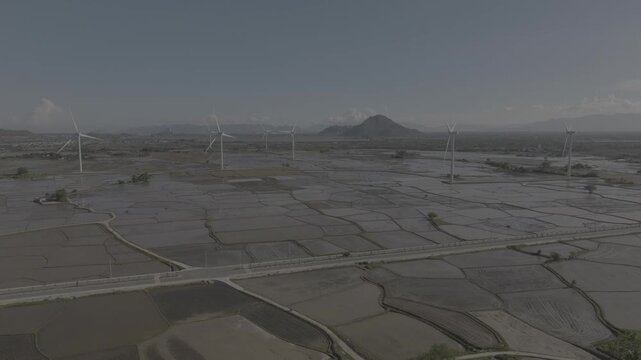 Aerial drone footage of Dam Nai Wind Farm in Khanh Hoa, Vietnam, featuring rows of wind turbines across coastal wetlands, showcasing renewable energy, sustainable power and scenic landscape.
