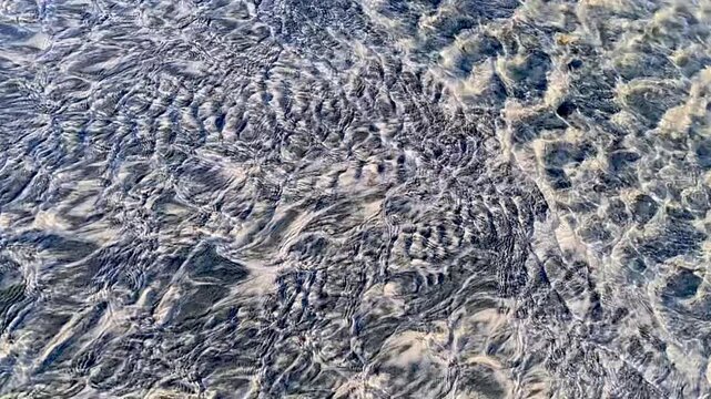 Slow motion of water In the shallows with a sandy bottom, on a sunny day.