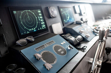 Digital dashboard with navigation monitor system, marine radar, VHF Radio and binoculars in ship captain bridge. Wheelhouse steering console on Nautical vessel transport. Modern boating technology © zephyr_p