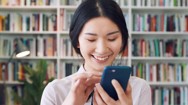 Student, scroll or Asian woman in library with phone, college education or laugh for social media meme. Happy, female person and browse on university campus with tech, online joke or funny news story