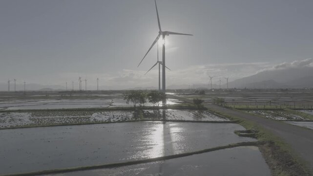 Aerial drone footage of Dam Nai Wind Farm in Khanh Hoa, Vietnam, featuring rows of wind turbines across coastal wetlands, showcasing renewable energy, sustainable power and scenic landscape.