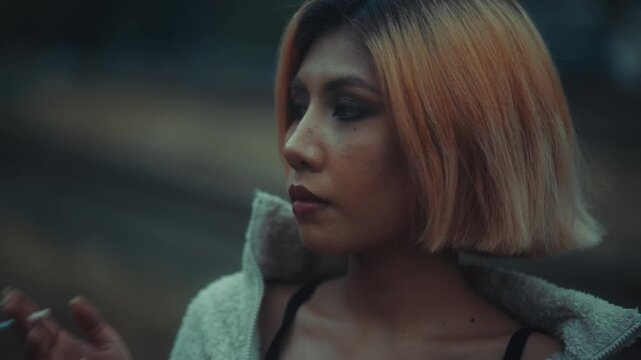 Young woman standing by railway tracks at dusk with fleece jacket
