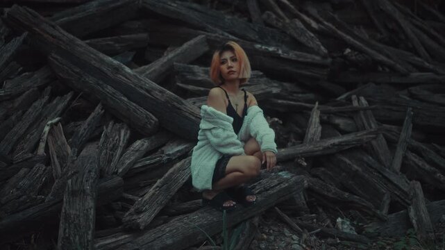 Young woman crouching on weathered driftwood in moody overcast light