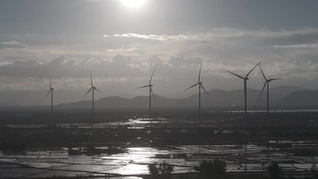 Aerial drone footage of Dam Nai Wind Farm in Khanh Hoa, Vietnam, featuring rows of wind turbines across coastal wetlands, showcasing renewable energy, sustainable power and scenic landscape.