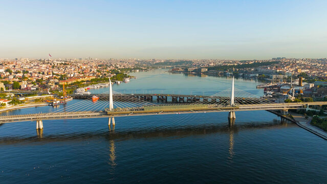 Istanbul, Turkey. Golden Horn Metro Bridge and Halic Station pedestrian crossing illuminated by morning sun over the bay. Aerial View