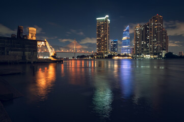 Fototapeta premium Dramatic twilight over Chao Phraya River featuring old shipyard and modern skyscrapers.