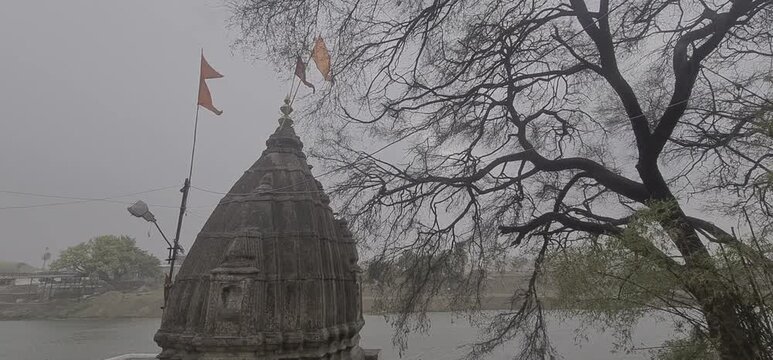 Ancient Stone Temple Top with Waving Saffron Flag in Windy Monsoon Weather of Ujjain, Madhya Pradesh, India 