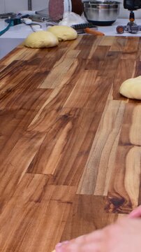 Male chef hands kneading sweet bread dough on the wooden kitchen table