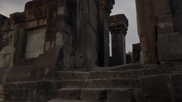 Moving shot at Prasat Hong Nang Sida in Champasak, Laos, sliding left while panning right across the doorway and weathered Khmer stone architecture.
