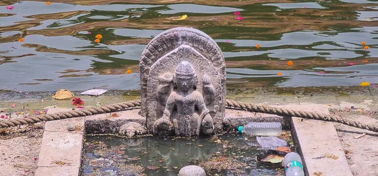 Environmental Pollution Near Sacred Hindu Deity Idol Surrounded by Water Trash and Waste at a RamGhat, Ujjain, Madhya Pradesh, India 