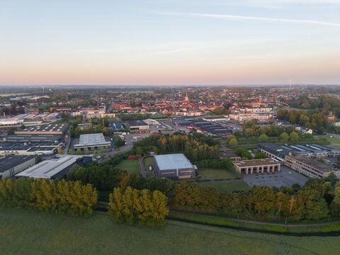 Diepenbeek, Belgium. Aerial drone view of suburban town with industrial zone and residential areas at sunrise
