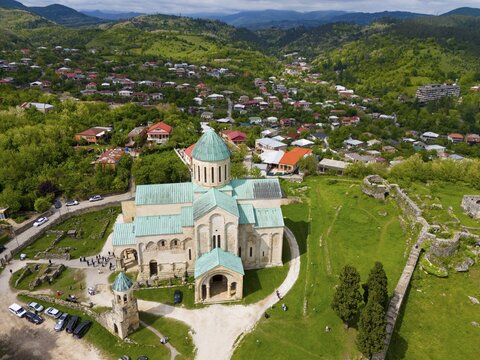 Cathedral with green roofs, surrounded by a village and green landscape, aerial view, Bagrati Cathedral, Church of the Dormition of the Most Holy Mother of God, UNESCO World Heritage Site, Kutaisi, Kutaisi, Imereti Region, Georgia