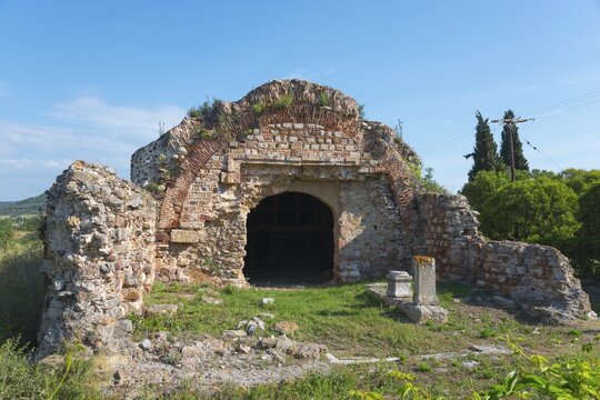 The ruins of an ancient structure with an arch, surrounded by trees under a clear sky, Archaeological Site of Traianoupolis, Loutra Traianoupoleos, Loutra Traianoupolis, Eastern Macedonia and Thrace, Greece
