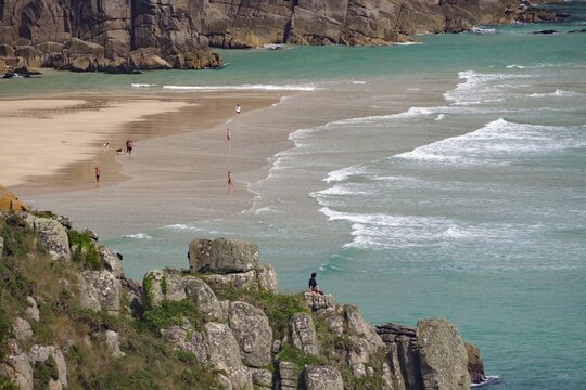 Blick auf Strand zwischen Klippen mit Menschen am Ufer und t&uuml;rkisfarbenem Meer, Aussichtspunkt, Porthcurno, St Levan, Cornwall, Gro&szlig;britannien