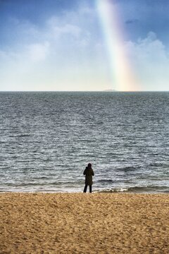 Stroller, tourist standing on the south beach, looking at the sea and rainbow in autumn, Wyk auf F&ouml;hr, F&ouml;hr Island, North Frisia, North Sea, Schleswig-Holstein, Germany