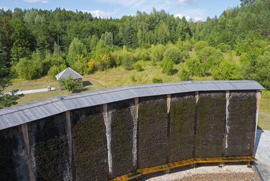 Curved wooden wall in front of a forest with lively green foliage under a blue sky, brine, graduation tower, spa town of Miłomłyn, Milomlyn, Lviv, Warmia-Masuria, Poland
