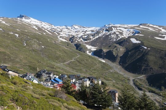 A mountain village with colourful houses in a snowy mountain landscape under a clear sky, left Pico del Veleta, Veleta peak, village Sierra Nevada, G&uuml;&eacute;jar Sierra, G&uuml;ejar, Sierra Nevada, Andalusia, Spain
