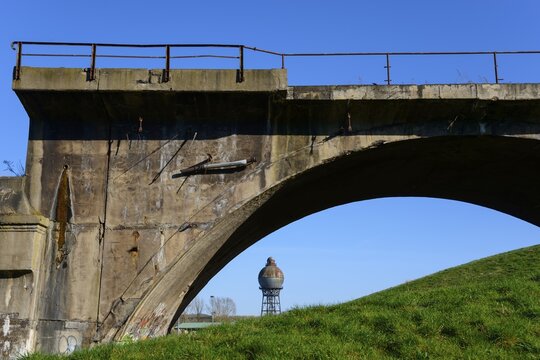Old concrete bridge in front of a blue sky with a water tank in the background, surrounded by meadow, spherical water tower, landmark, Ilseder H&uuml;tte, Ilsede, district of Peine, Lower Saxony, Germany
