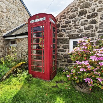 Red telephone box with defibrillator inscription, Cornwall, England, Great Britain