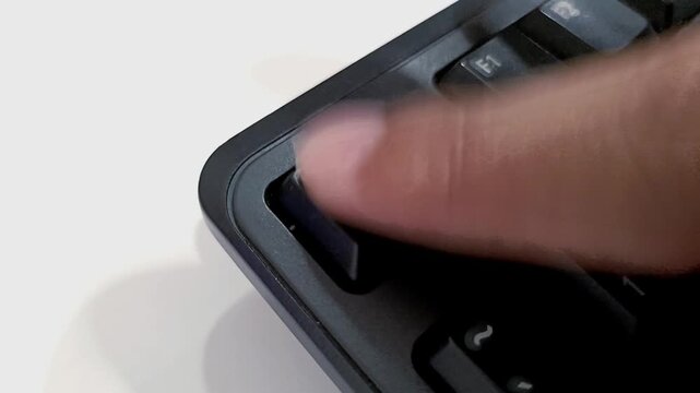 Close up of a finger pressing the Esc key on a black computer keyboard repeatedly with urgency.