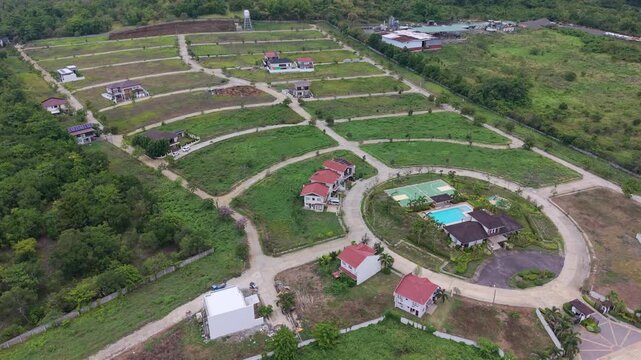 Aerial view of subdivision road grid and land development in Puerto Princesa Palawan with small buildings lots access roads and surrounding green terrain