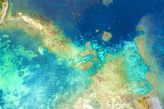 Aerial view of vibrant coral reefs and turquoise ocean water with clear underwater rock formations English Harbour, Saint Paul, Antigua and Barbuda.