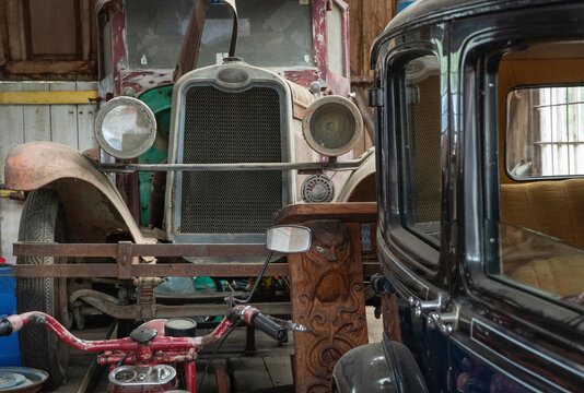 Oldtimers in vintage wooden garage in Waimamaku New Zealand. Storage with vintage car and motocycles.