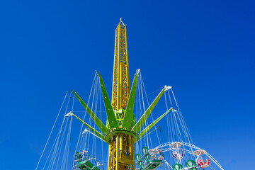 Giant swing tower ride against a clear blue sky in amusement park. Thrill fairground attraction carousel close up. © Igor