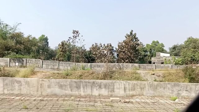 Train outside cool environmental close-up view of railway travel fun with electric wires, greenery trees, plants, grass, bush, construction work, house and cloudy sky nature in winter season in india.
