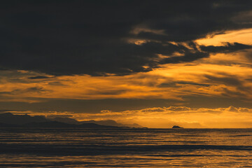 Fototapeta premium Dramatic Orange Twilight Sky Over Sea and Mountain Silhouettes