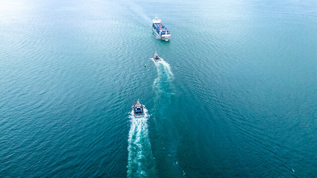 Cargo container ship convoy with escort vessels navigating in a straight line sequence across the blue ocean. Maritime logistics fleet management and secure shipping channel transport.