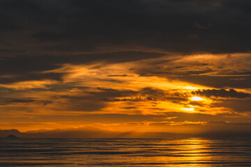 Fototapeta premium Dramatic Orange Twilight Sky Over Sea and Mountain Silhouettes