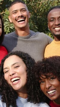 Vertical video: Laughing group posing in park as camera pulling back, showing bright tops and hoops