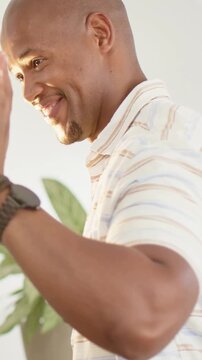 Vertical video: Smiling man in polo shirt, watch, giving hi-five to child at home counter keys