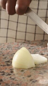 Vertical video: Slicing cook's hand lifting knife to onion in kitchen, prepping slices, copy space