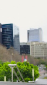 Vertical video: Pan revealing woman in pink knit walking past plaza, holding maroon bag, copy space