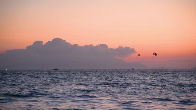 Parasailing Over Calm Sea at Sunset With Boats and Distant Mountains