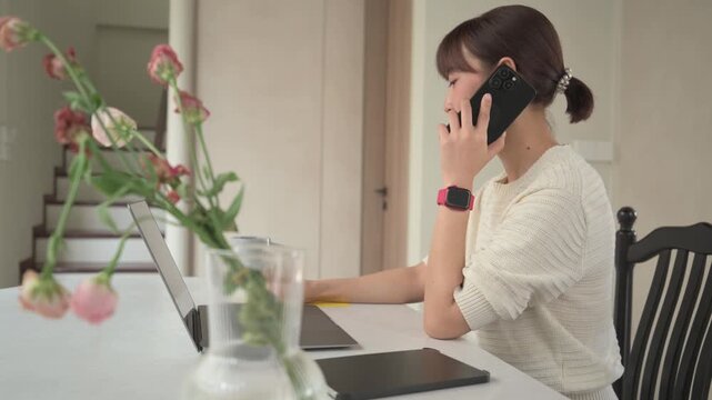 Engaged asian woman at home working remote as business consultant studying online utilizing laptop computer and smartphone assistive technology