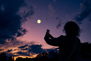 Obraz premium Amateur astronomer with smartphone photographing and observing stars, planets, Moon and other celestial objects.