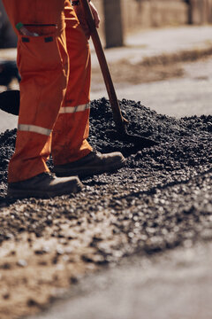 Construction worker working on a new asphalt layer on a public street.