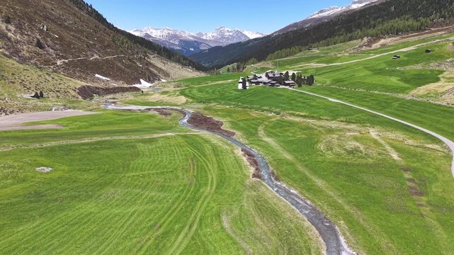 Aerial view of the Seitig Valley in Davos in the wakening spring time with the village chapel and winding brook.