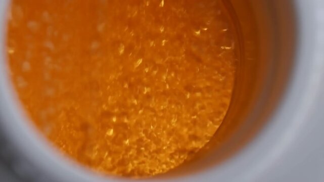 Orange textured liquid in a round container seen from above