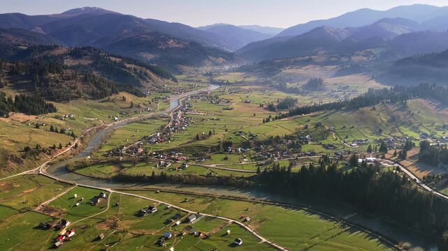 Aerial drone view of Ciocanesti area in Bucovina, Romania, showcasing rolling hills, patchwork fields, and dispersed traditional homes connected by winding rural roads