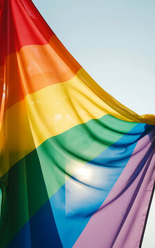 Vibrant rainbow flag waving in the wind with colorful stripes and sunlight shining through fabric