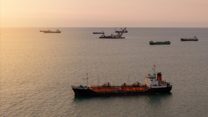 Fototapeta premium LPG tanker ship transporting liquefied petroleum gas near an industrial port terminal at twilight. Global energy logistics, maritime shipping industry, and fuel supply chain.