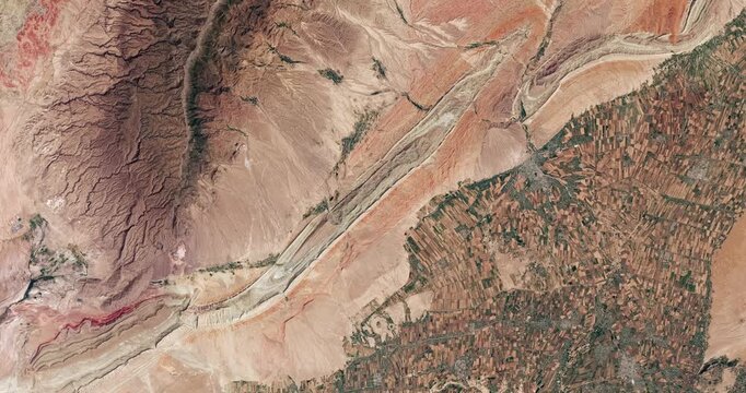 Bird's eye view on agricultural landscape in dry area. Camera is moving right. Animation based on image by NASA