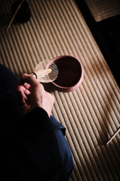Hands holding a bamboo whisk during a Japanese tea ceremony