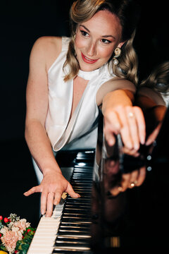 Elegant woman posing at a piano in a dramatic setting