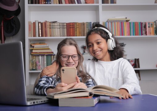 Two diverse young friends smile at smartphone