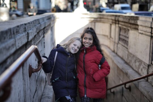 Two happy girl friends smiling on city stairs